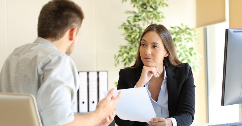Duas pessoas em conversa profissional, uma delas ouvindo com atenção